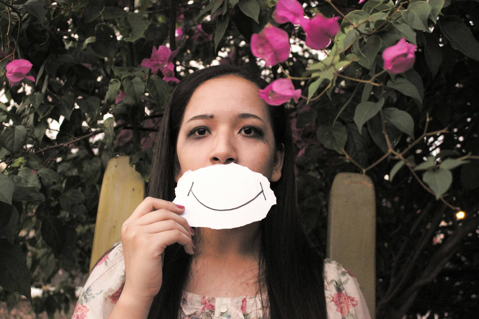 A woman holding a piece of paper with smiling lips drawing