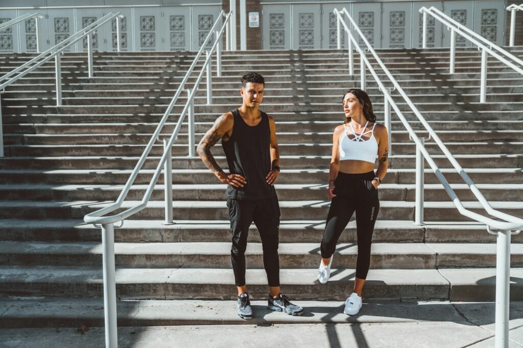 A man and a woman standing on steps dressed for their workout class.