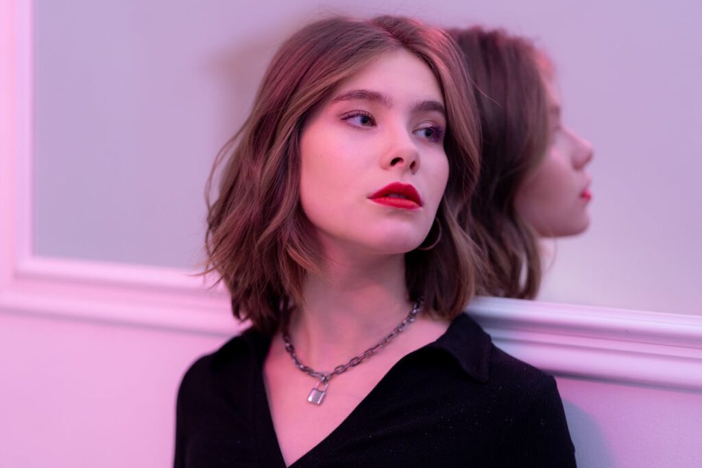 A woman leaning against a wall with a well-defined jaw 