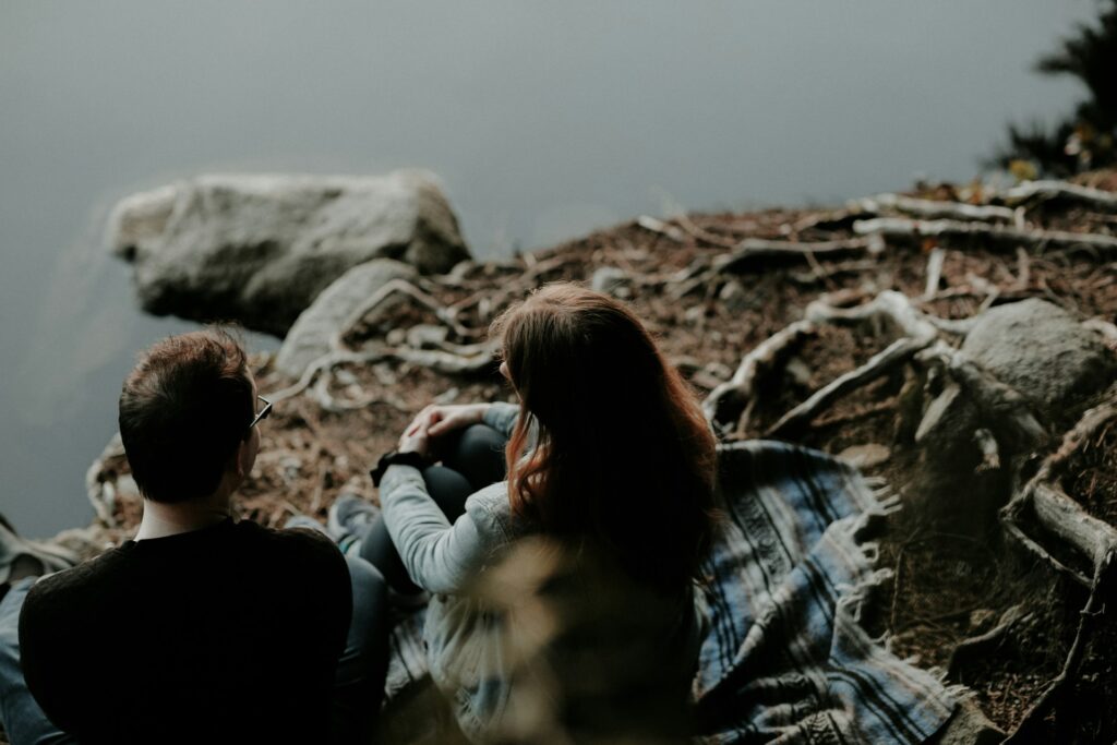 A man and a woman sit on a blanket next to a river. They're likely discussing if hormone-free birth control is right for them.