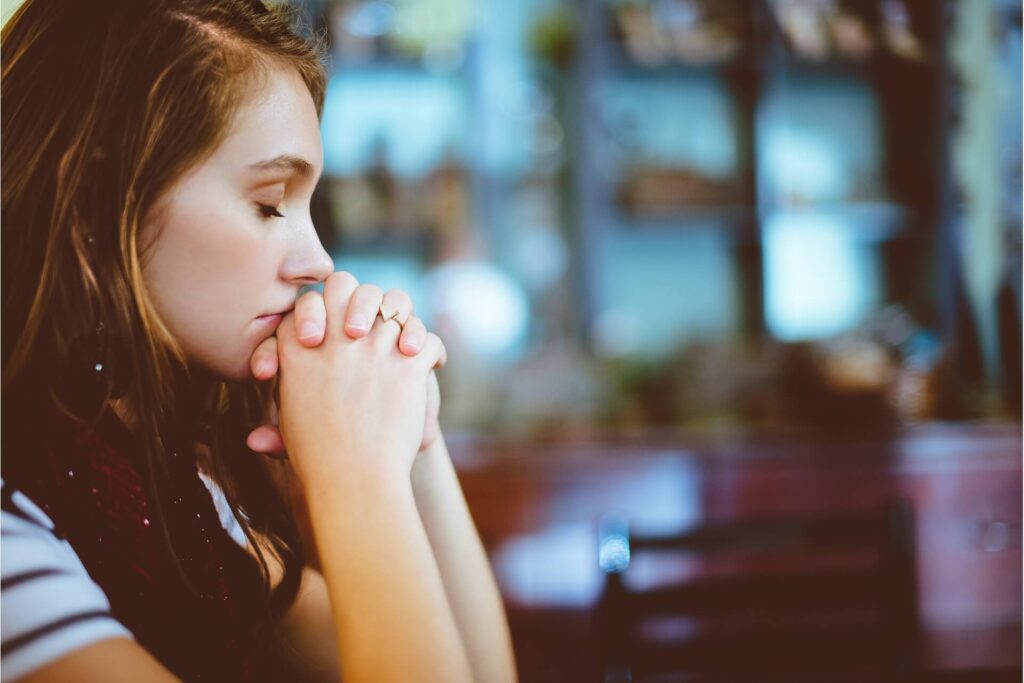 An upset young woman with her eyes closed resting her head on her hands. 