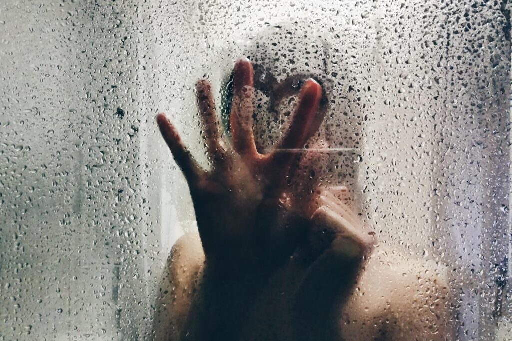 hand on wet glass wall