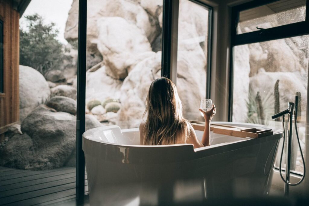 woman in bath with glass looking at rocks