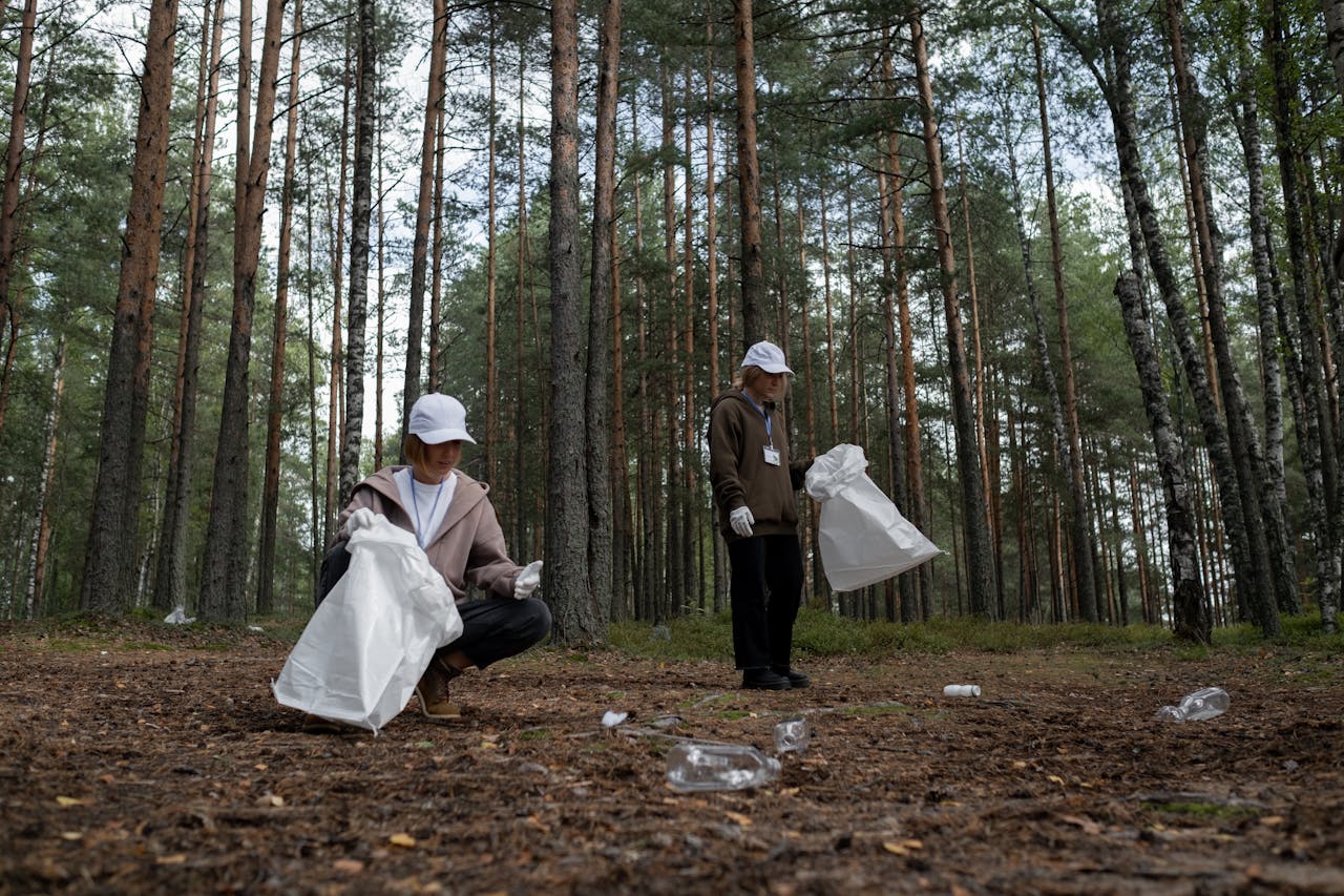 Two women picking up litter in a forest