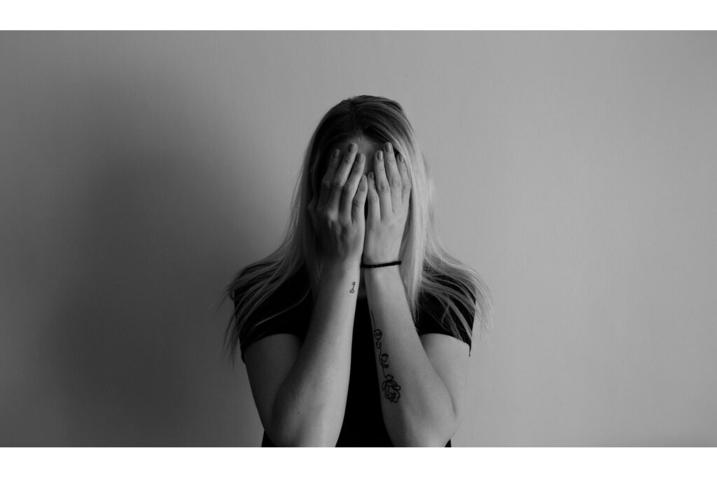 A young woman covering her face with her hands. 
