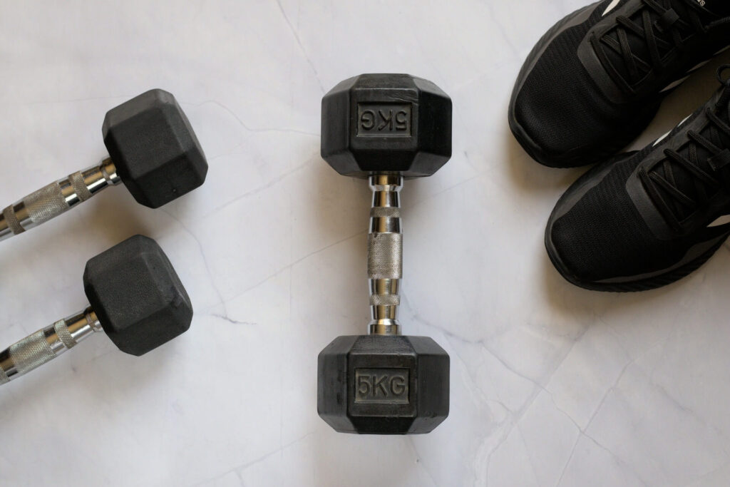 A person standing near dumbbells on a marble floor