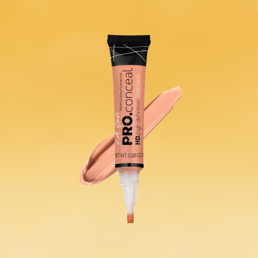 A tan-colored tube of L.A. Girl's Pro.conceal concealer sits against the yellow Body+Mind background. A smear of the product is behind the tube.