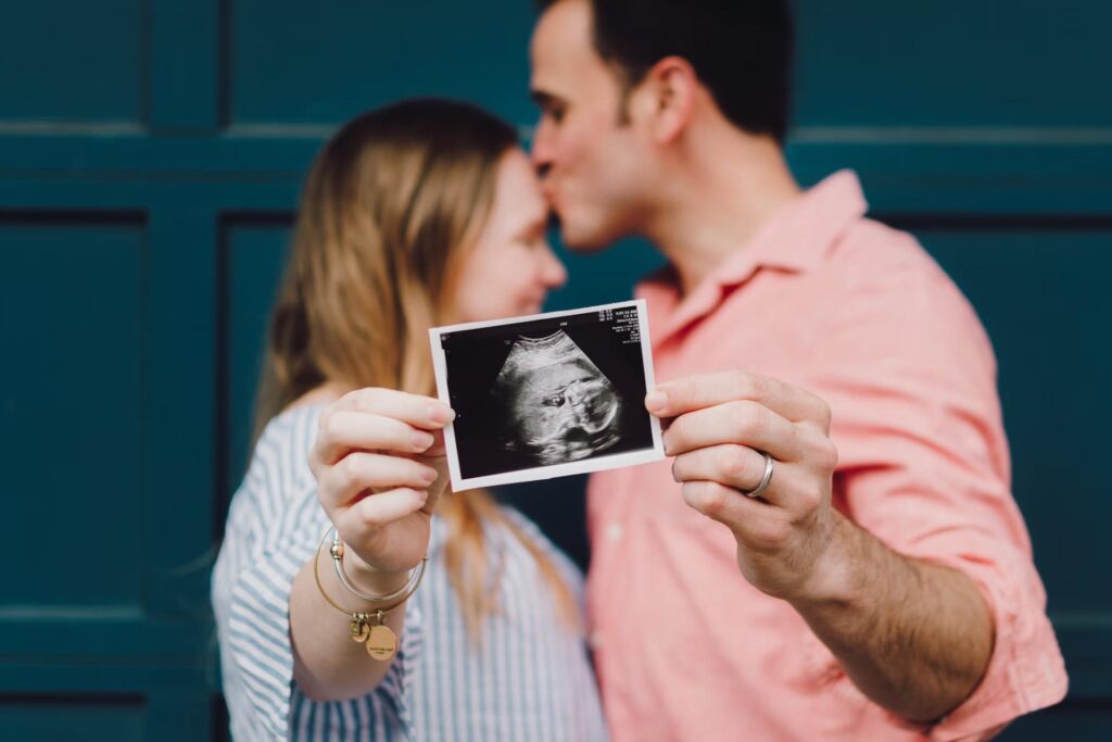 man and woman holding ultrasound photo for the camera