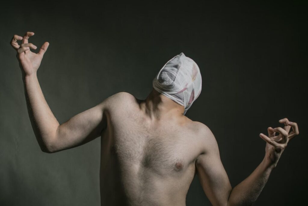 topless man in pain with bandage around his head