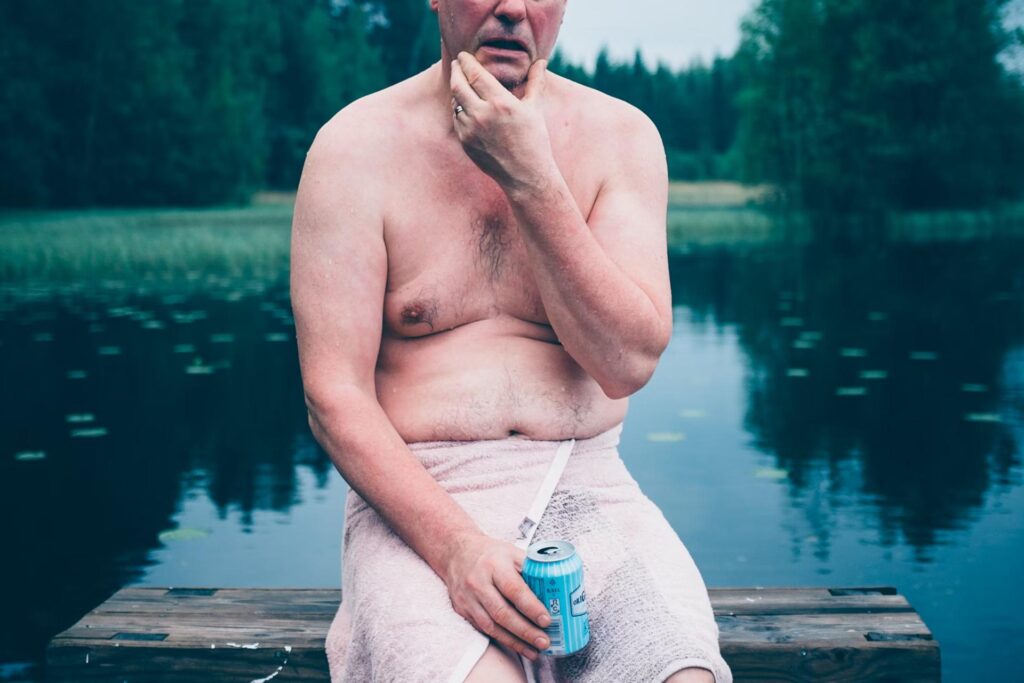 topless man wrapped in towel in front of lake