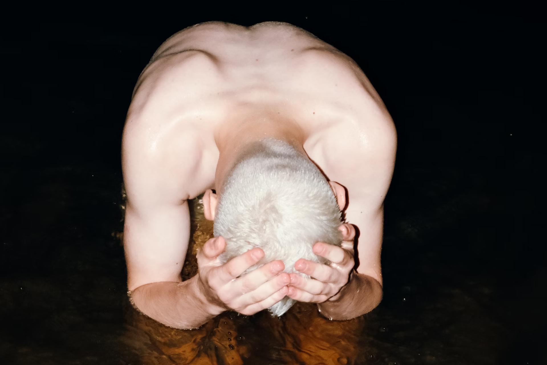 man with bleached hair holding his head