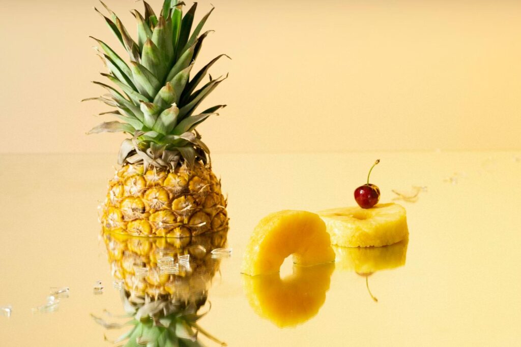 cut pineapple on yellow background with cherry