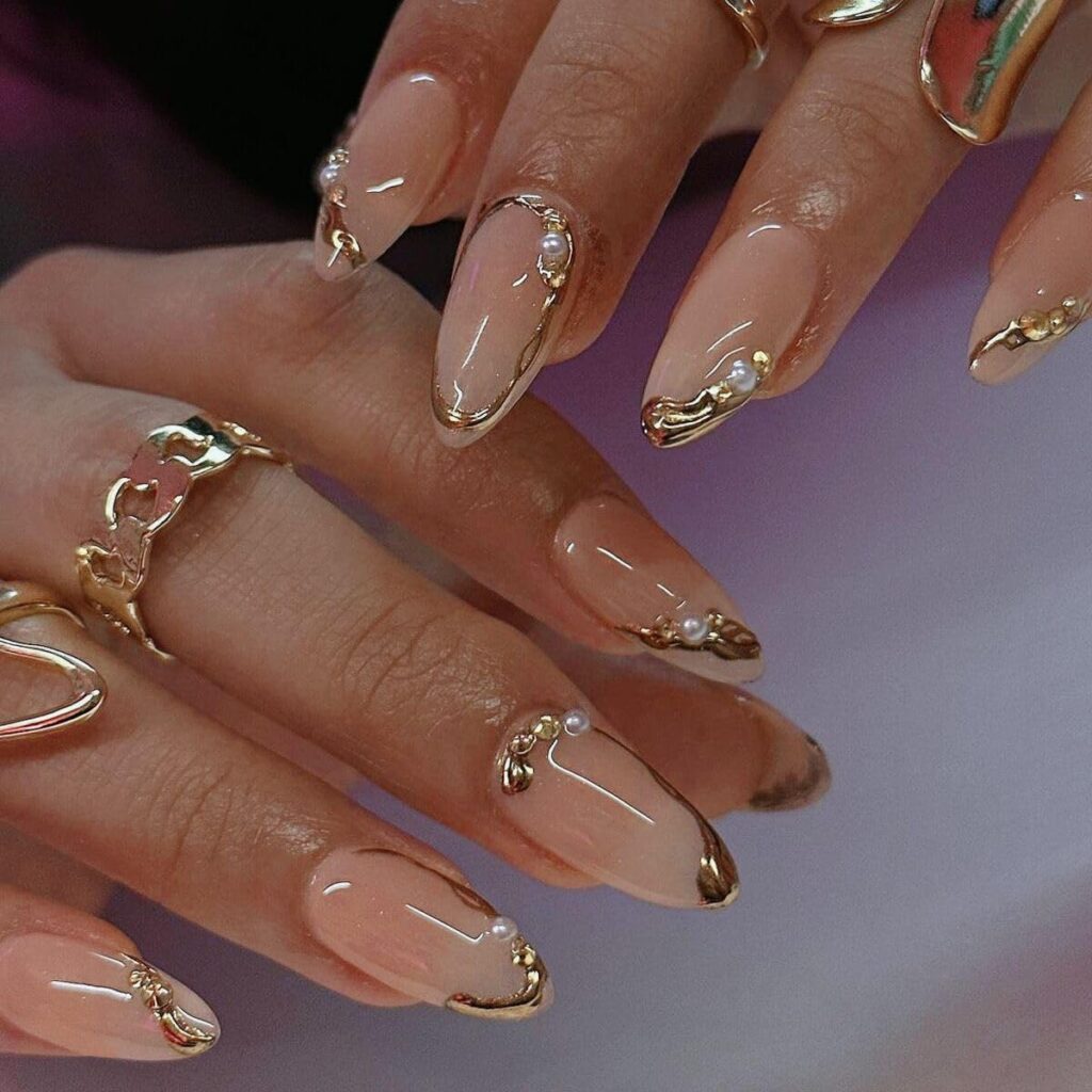 A woman wears a pair of gold-line press-on nails with gold rings. They're among the best press-on nails that last the longest.