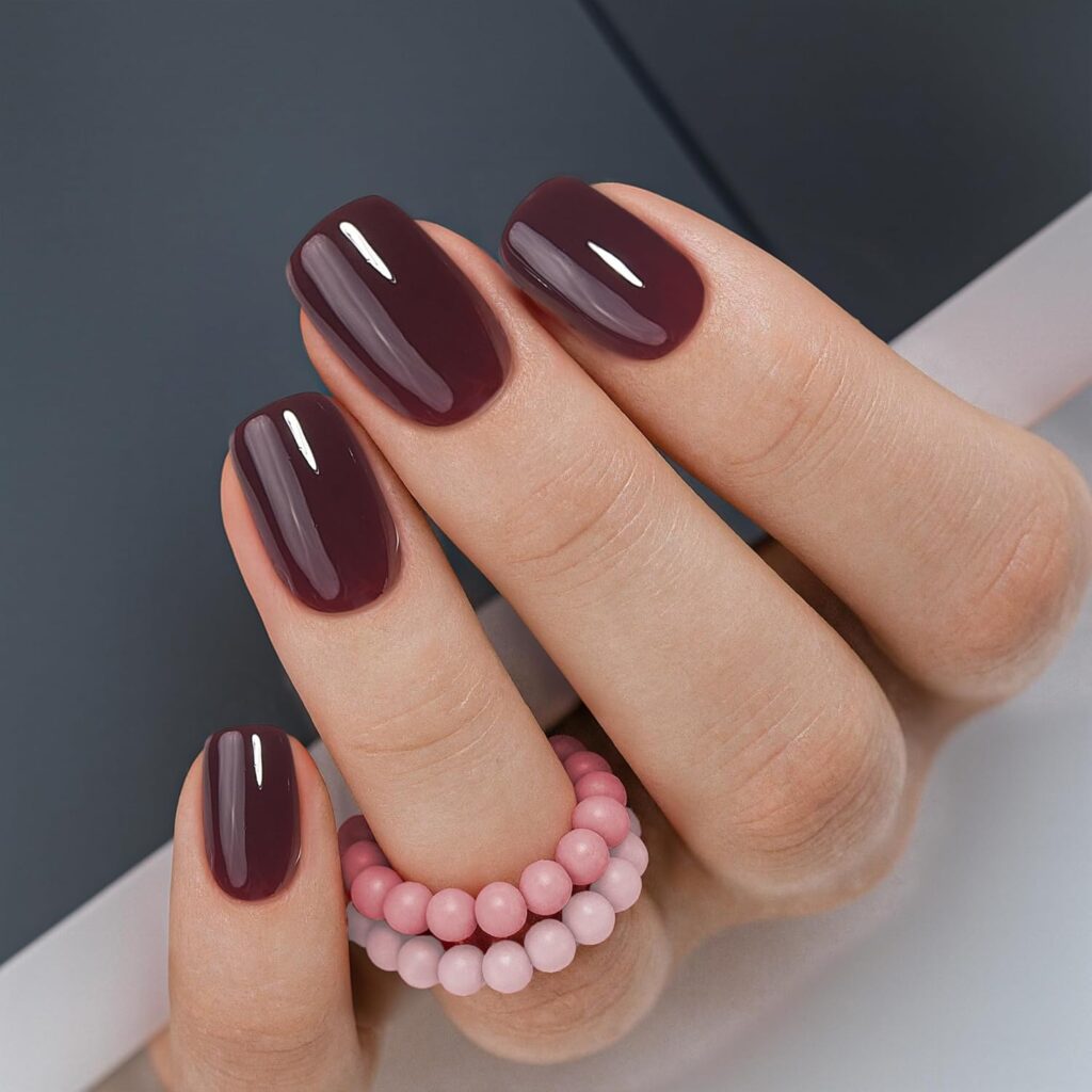 A woman wears red Curvlife nails with two pink bead rings.