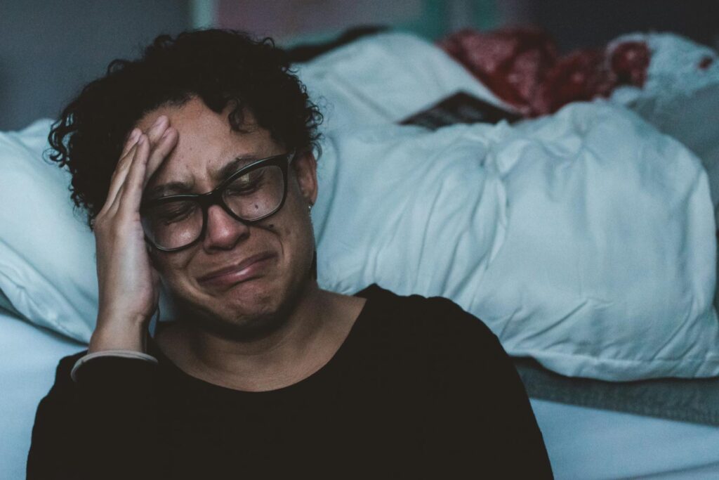Woman crying in front of bed