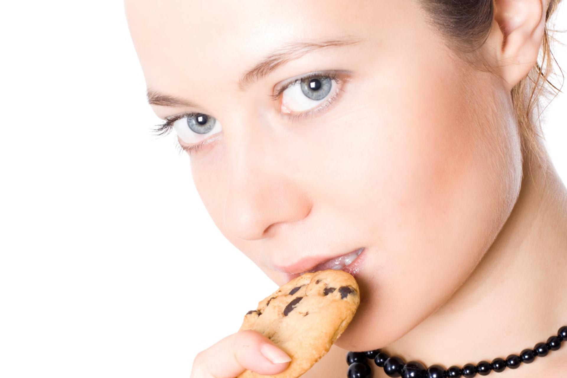 woman with black necklace eating cookie