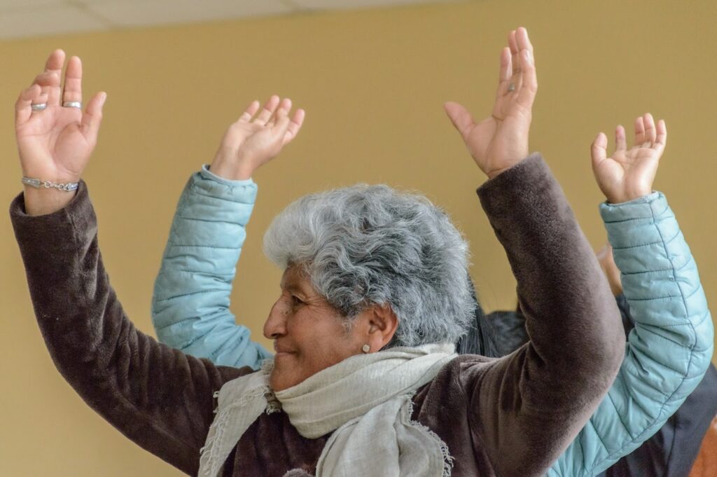 an older woman with her hands up in the air doing an exercise