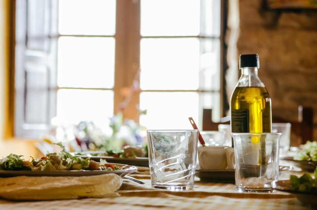 Two empty glasses and a bottle of olive oil on a kitchen counter