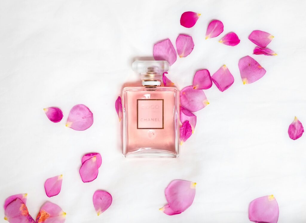 A bottle of perfume is elegantly placed among pink flower petals, creating a fragrant and visually appealing scene.